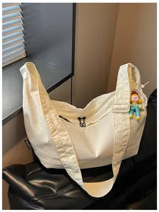 Detail van crème nylon crossbodytas met lichtgewicht stof en een schattige poppenhanger