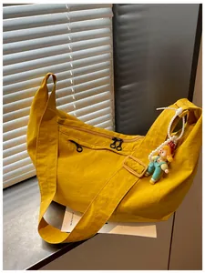Detail van een casual gele nylon crossbodytas voor dames met een schattige poppenhanger.