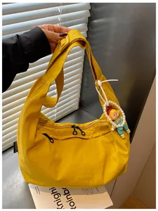 Gedetailleerd overzicht van een gele nylon draagtas met een schattige poppenhanger