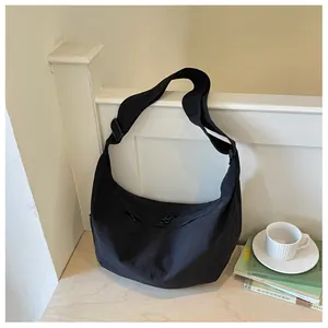 Close-up van een lichte zwarte nylon crossbodytas in een gezellige binnenhuisopstelling