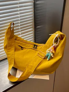 Grote gele nylon crossbodytas met een casual, soepel ontwerp en een schattige poppenhanger