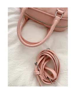 Close-up of pink bowling handbag with pebbled leather texture and matching strap