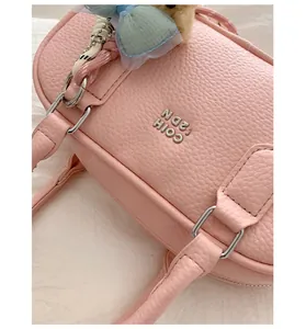 Close-up of a stylish pink pebbled leather bowling bag featuring a sleek metallic logo detail.