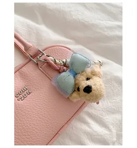 Detailed close-up of a stylish pink leather bowling bag featuring a cute teddy bear charm