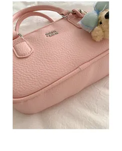 Detail view of pink pebbled leather bowling handbag with a cute bear charm