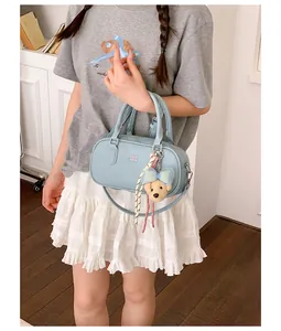 Detailed view of stylish light blue bowling handbag with a cute teddy bear charm