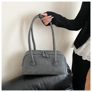 Detailed view of a grey textured Boston bag with long shoulder straps held by a model