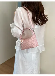 Pink checkered tweed dumpling bag with metallic studs and a delicate pearl lace charm.