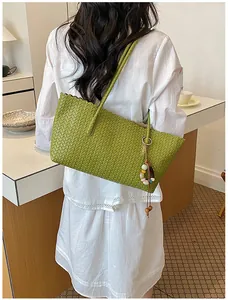Vue détaillée d'un sac cabas en cuir tressé vert avec un accessoire de perles coloré