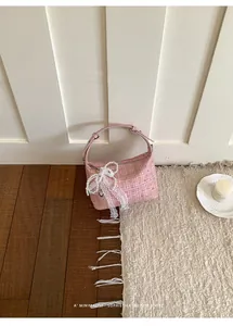 Detailed view of a pink plaid handbag featuring delicate lace bow and pearl charm accents