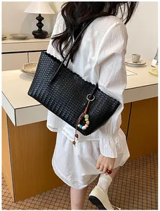 Vue détaillée du grand sac cabas noir tressé avec breloque décorative sur un modèle