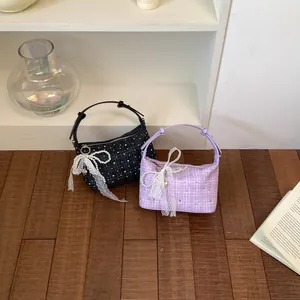 Detailed view of two tweed plaid handbags in black and lavender with lace bows.