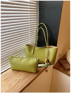 Détail d'un sac cabas tissé vert et d'une pochette assortie avec charm en perles