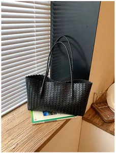 Vue détaillée d'un grand sac cabas noir tissé avec bords festonnés et deux fines bandoulières