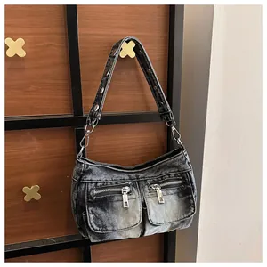 Close-up of a vintage washed denim shoulder bag featuring dual front zipper pockets