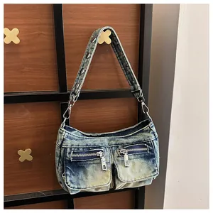 Detail of a vintage washed denim shoulder bag with multiple zippered pockets