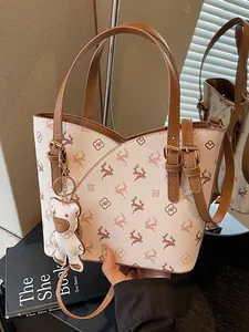 Elegant cream and brown monogram commute bucket bag with bear charm and adjustable strap