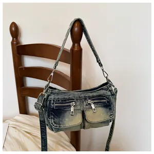 Vintage acid wash denim crossbody bag with multiple zipper pockets hanging on a wooden chair
