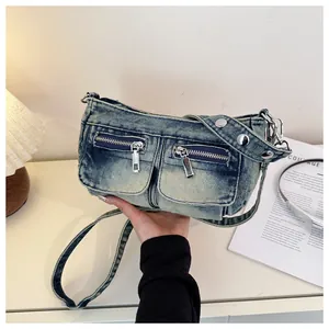 Detailed view of a vintage distressed denim crossbody bag with zipper pockets and studs.