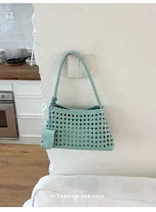 Vue détaillée d'un sac seau tissé ajouré vert menthe suspendu à un mur blanc chic