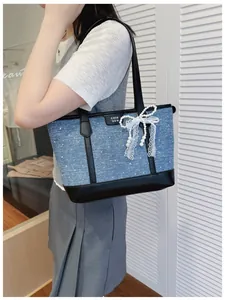 Stylish denim tote bag featuring a decorative lace bow and pearls on the shoulder strap.