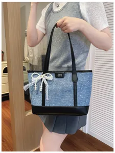 Large denim tote bag with black leather trim and lace pearl bow detail