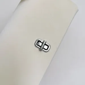 Makroansicht des eleganten silbernen Drehverschlusses an einer weißen Handtasche