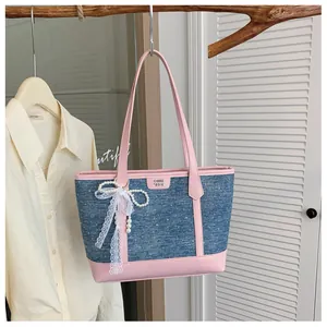 Chic blue denim tote bag featuring pink leather trim and elegant lace pearl bow accessory