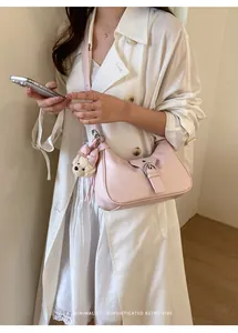 Sofisticado bolso hobo rosa claro con hebilla y detalle de colgante de perro de peluche