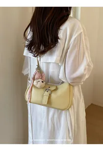 Modelo con un bolso retro amarillo pálido en forma de dumpling con un osito colgante