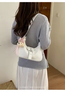 Vista trasera de mujer con un bolso hobo blanco minimalista y un adorno de peluche