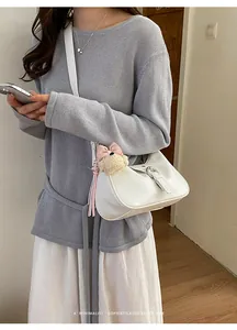 Bolso bandolera blanco retro minimalista llevado por una modelo en ambiente interior