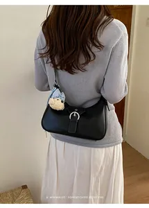 Bolso de hombro retro negro minimalista con un lindo amuleto de osito de peluche en un modelo