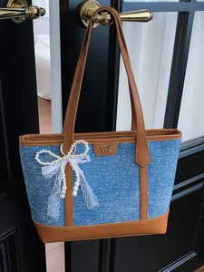 Stylish large denim tote bag for women featuring pearl bow charm and leather trim