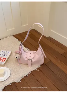 Vista detallada de un bolso retro rosa para axila con colgante de oso de peluche.