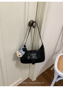 Bolso de hombro retro negro minimalista colgado en el pomo de una puerta en detalle