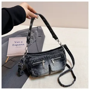 Close-up of washed denim shoulder bag with metal zipper pockets and grommet strap.