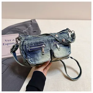 Detail macro view of a vintage blue denim crossbody bag featuring functional zipper pockets