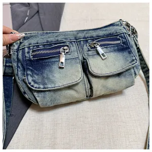 Detail shot of a casual denim crossbody bag with double front zippers and wide strap.