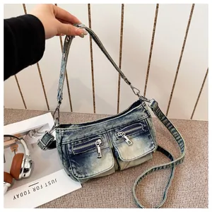 Close-up of vintage washed denim crossbody bag with functional zip pockets
