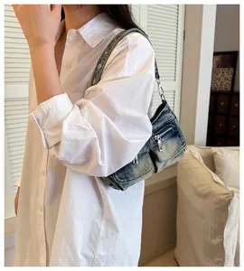 Vintage washed denim underarm shoulder bag with functional zipper pockets shown on model