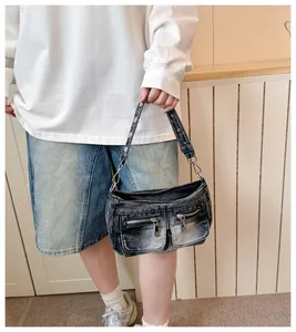 Detailed view of a trendy washed black denim shoulder bag featuring silver zippers and rivets