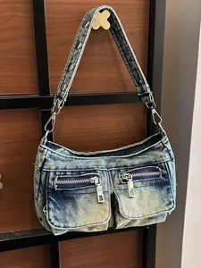 Washed denim shoulder bag for women featuring front zipper pockets and a studded strap.
