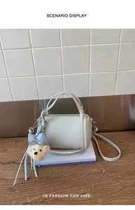 Mint green cylinder handbag with teddy bear charm on wooden table and tiled background