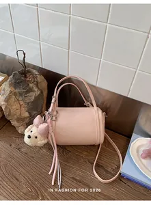 Close-up of a pink cylinder bag with a cute plush dog charm on a rustic wooden table