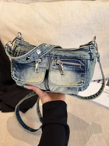 Trendy washed blue denim crossbody bag featuring dual front pockets and silver metal zippers