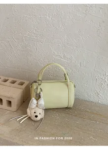 Elegant light yellow cylinder pillow bag featuring a cute plush teddy bear charm detail