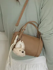 Stylish brown faux leather barrel pillow bag for women with cute white plush dog charm