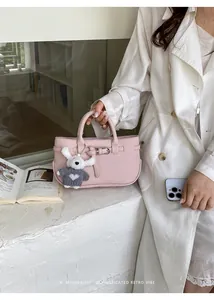 Close-up of a minimalist pink leather handbag with a cute plush bunny charm detail