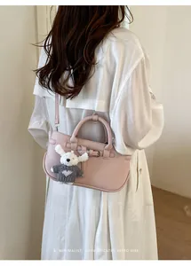 Back view of a chic pink handbag with a cute rabbit charm against a white shirt